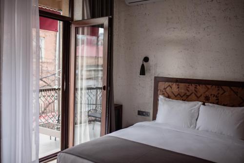 a bedroom with a bed and a window with a balcony at Kazma Boutique Hotel in Tbilisi City