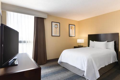 a hotel room with a bed and a flat screen tv at Embassy Suites by Hilton Bloomington/Minneapolis in Bloomington