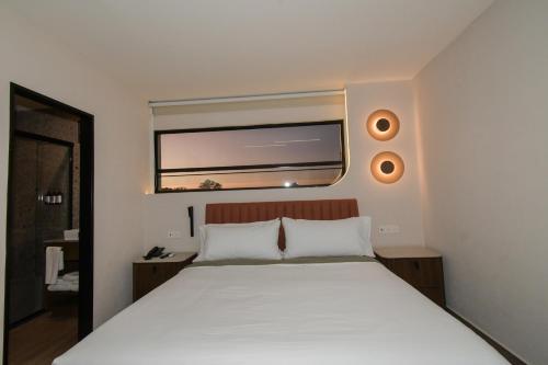a bedroom with a large white bed with a window at Expo Satelite 2750 Hotel & Suites in Guadalajara