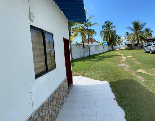 a white house with a window and a yard at Cabaña en tolú, Sucre, a unos pasos del mar in Puerto Viejo