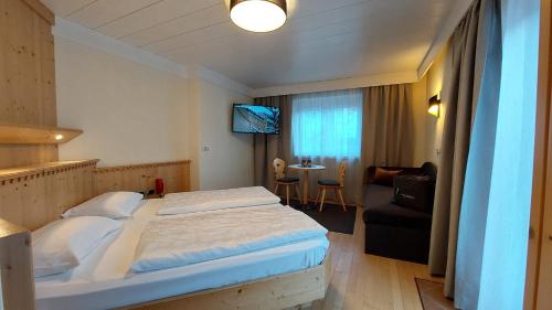 a bedroom with a large bed and a living room at Hotel Cristallo in Santa Cristina in Val Gardena