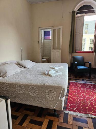a bedroom with a bed and a chair and a red rug at Varzea Palace Hotel in Teresópolis