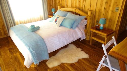 a bedroom with a bed with blue pillows at Refugio del Chucao in Llanada Grande