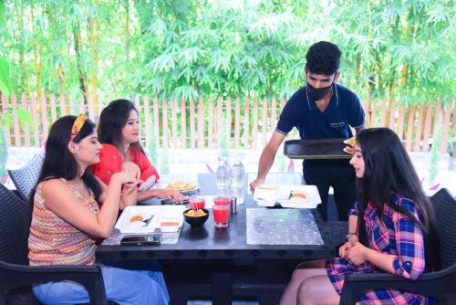 a group of people sitting at a table eating food at The Mountain Shades Resort in Madikeri