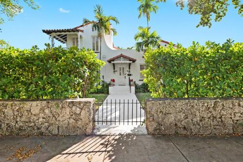 a white house with a gate and trees at Casa Coral in Miami
