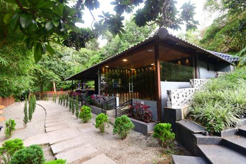 a small building with benches in a garden at The Mountain Shades Resort in Madikeri