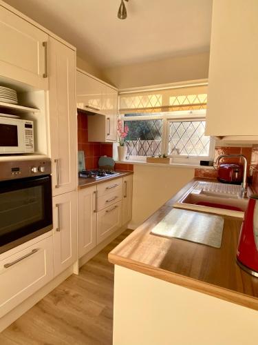 a kitchen with white cabinets and a counter top at Spacious bungalow Air con & Wi-fi in Sidley