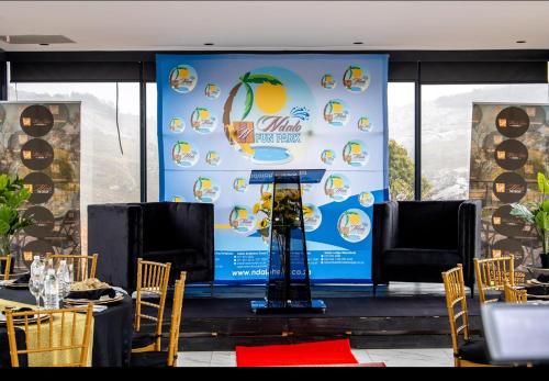a stage with a sign on it with tables and chairs at Ndalo Lodge Oshoek in Oshoek