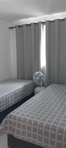 a bedroom with two beds and a window with curtains at Village - Cond Planeta Água - Jacuípe in Barra de Jacuípe