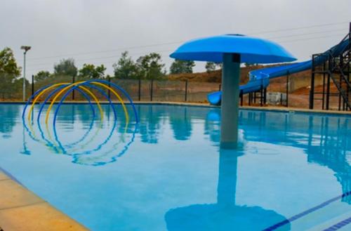 a pool with an umbrella and a water slide at Ndalo Lodge Oshoek in Oshoek