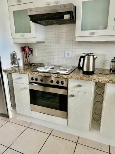 a kitchen with white cabinets and a stove top oven at Waters Edge Guest House in Jeffreys Bay