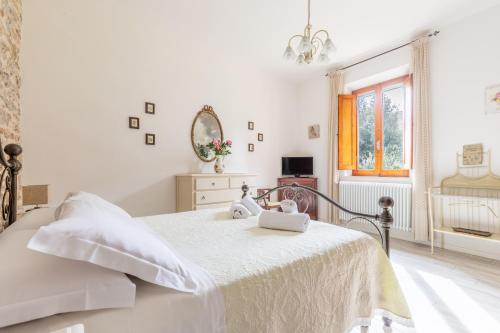 a white bedroom with a bed and a mirror at Fabio Apartments San Gimignano in San Gimignano