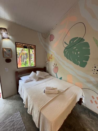 a bedroom with a bed and a wall with a flower mural at Pousada Flor do Xandó Caraíva in Caraíva