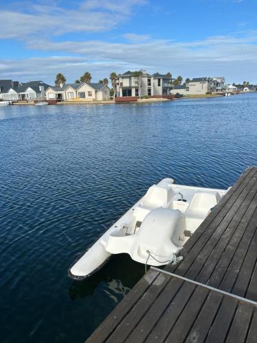 a boat sitting on the water next to a dock at Waters Edge Guest House in Jeffreys Bay