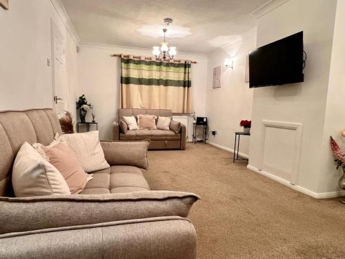 a living room with a couch and a television at J&J stays 5 bedroom detached house in Peterborough with parking in Peterborough