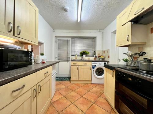 a large kitchen with a washer and dryer in it at J&J stays 5 bedroom detached house in Peterborough with parking in Peterborough