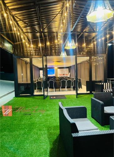 a room with green grass and chairs and lights at Ndalo Lodge Oshoek in Oshoek