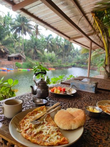 een tafel met een bord pizza en een waterkoker bij Dwarka Beach Resort Goa in Cola
