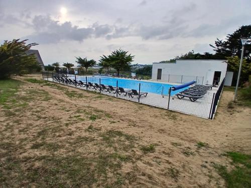 une clôture avec une piscine en face d'un bâtiment dans l'établissement Duplex proche de la mer avec piscine, à Guidel