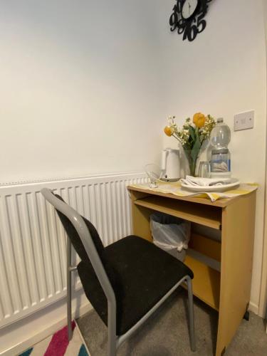 a desk with a chair and a vase of flowers at Jmk home in Lexden