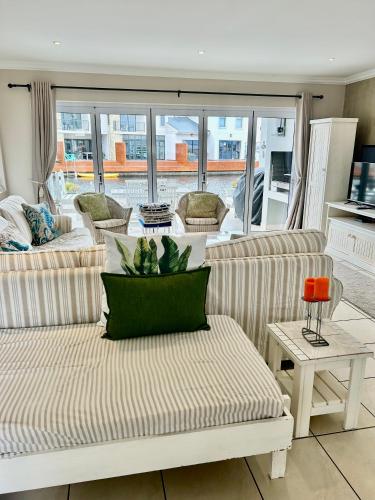 a living room with two couches and a table at Waters Edge Guest House in Jeffreys Bay