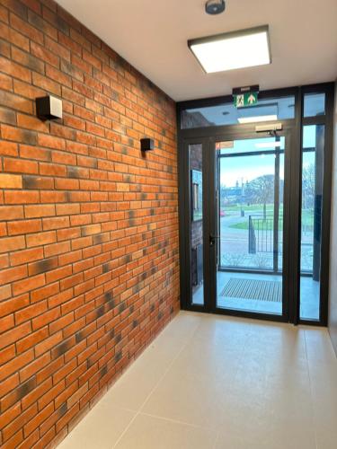 an empty room with a brick wall and a glass door at Apartament Premium Zamkowa B21 in Tczew