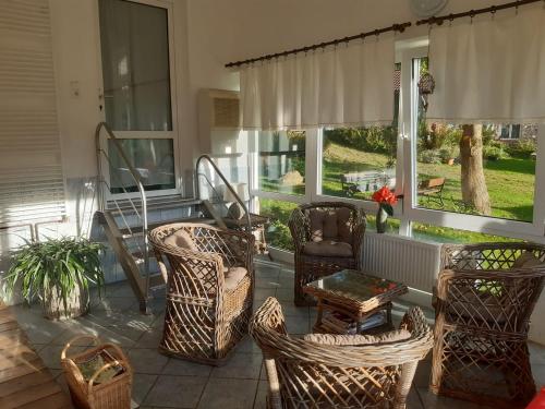 a screened in porch with wicker chairs and tables at Penzion Montana in Zelená Lhota