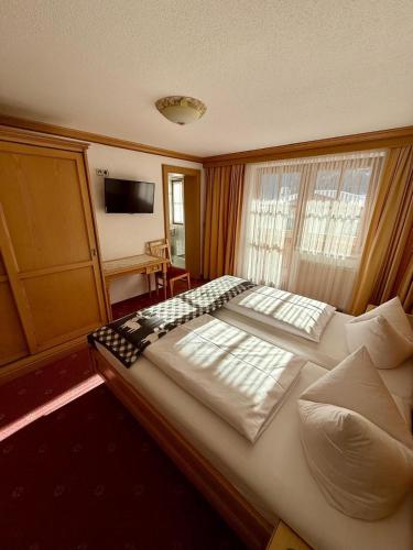 a bedroom with a large white bed with a window at Appartement Landhaus Jehle in Flirsch
