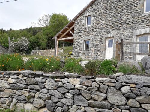 a stone wall in front of a stone house at Maison de village gîte de "La Roche" in Saint-Julien-Chapteuil