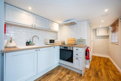 a kitchen with white cabinets and a sink at Holly House Studio, Lavenham in Lavenham