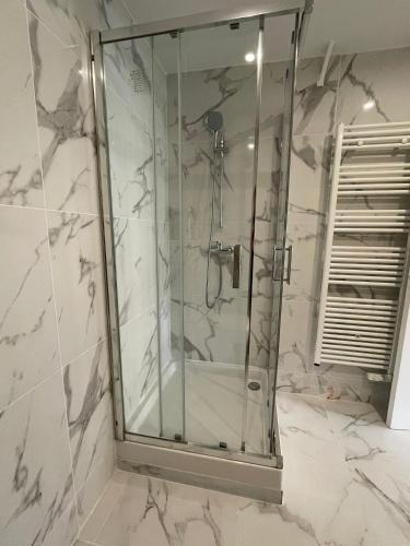 La salle de bains en marbre blanc est pourvue d'une douche en verre. dans l'établissement Studio Côte Bleue, à Boulogne-sur-Mer