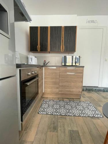 - une cuisine avec des placards en bois et un tapis au sol dans l'établissement Studio Côte Bleue, à Boulogne-sur-Mer