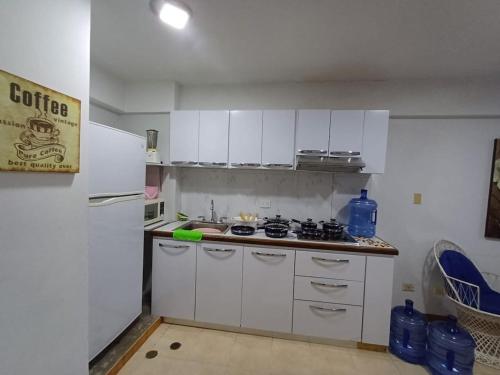 a kitchen with white cabinets and a white refrigerator at Atenea Suite Apartment in Porlamar