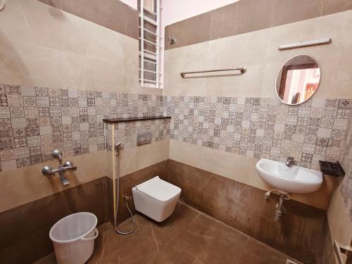 a bathroom with a sink and a toilet and a mirror at The Whiteglow Elite in Chennai