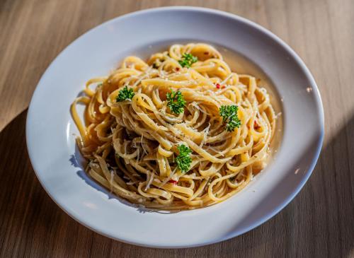 a bowl of pasta with parsley on a table at Indie Stays Mumbai International Airport in Mumbai