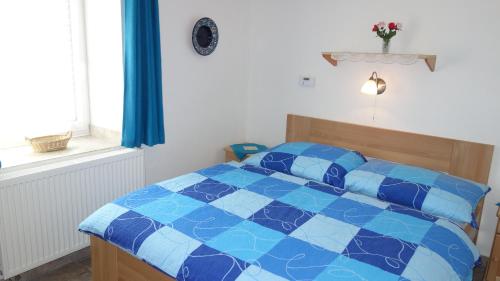 a blue and white bed in a room with a window at Guest House Melusine in Loučná pod Klínovcem