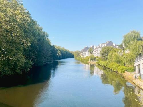a view of a river with trees and buildings at Les Voiles Blanches - Appartement dans un château in Caen