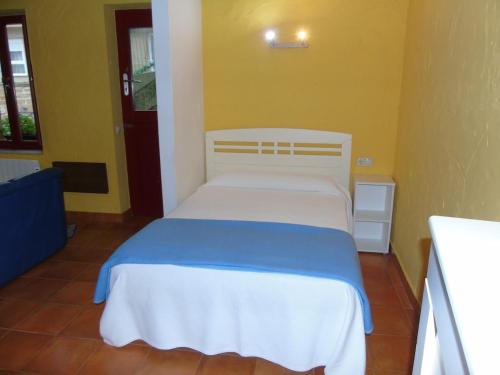 a bedroom with a white bed with a blue blanket at Loft O Viñal in Muros