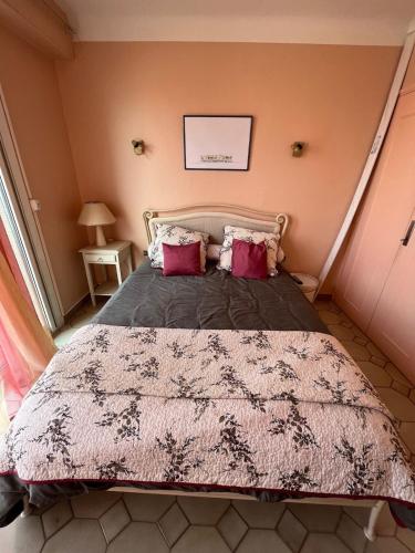 une chambre avec un grand lit avec des oreillers rouges dans l'établissement Appartement entre plage et ville, à Sainte-Maxime