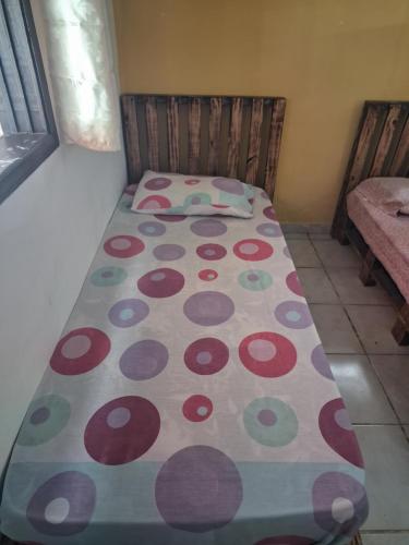 a small bed with a polka dot blanket on it at Renovo Beija-flor Hostel e Espaço Terapêutico in Bertioga