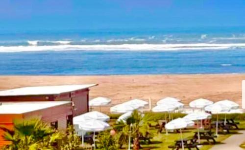 a beach with a bunch of white umbrellas and the ocean at Blanca beach in Sidi Rahal