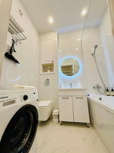 a white bathroom with a washing machine in it at Esil Riverside Elite Apartments in Astana