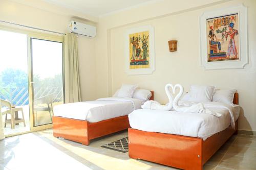 two beds in a room with a balcony at Holiday Dream Of Luxor in Luxor
