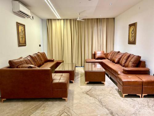 a living room with leather couches and a table at Heartland- Ganga Villa with Jacuzzi and private lift in Rishīkesh