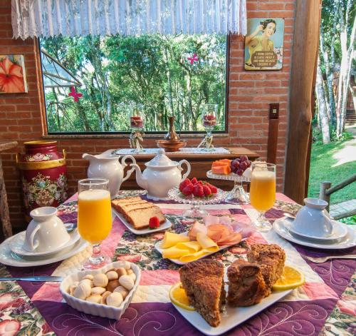 a table with breakfast foods and orange juice on it at Pousada Alto da Neblina in Monte Verde