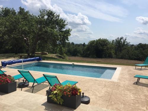 a swimming pool with blue chairs and a table at Maison avec vue et sa piscine chauffée privative in Bessas