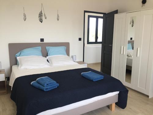 a bedroom with a large bed with two blue towels on it at Maison avec vue et sa piscine chauffée privative in Bessas