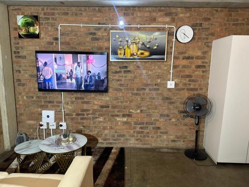 a living room with a tv on a brick wall at The Hills by maboneng in Johannesburg