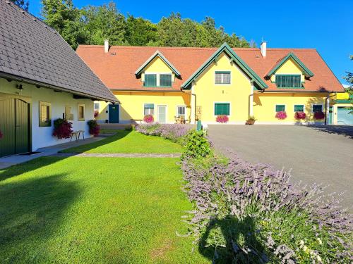 ロイトシャッハにあるFerienhaus KAUSCHLERHOFの紫の花の庭のある黄色い家
