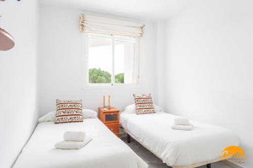 two twin beds in a room with a window at Retama Golf by Cadiz Time in Novo Sancti Petri